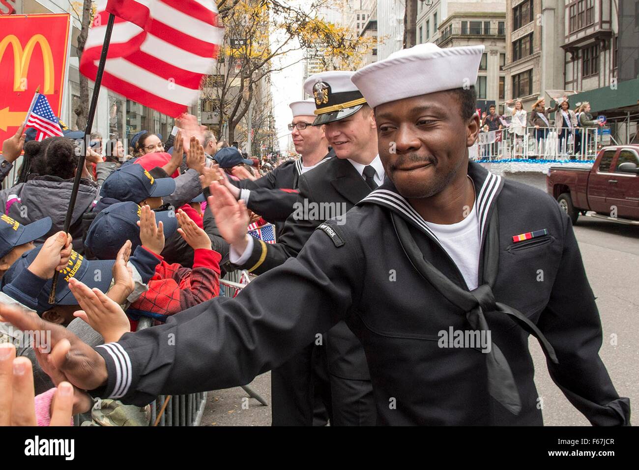 Gli Stati Uniti I marinai della marina dal trasporto anfibio dock nave USS New York salutare le persone si sono riuniti per l annuale Giornata dei veterani parade durante la settimana dei veterani Novembre 11, 2015 nella città di New York, NY. Foto Stock