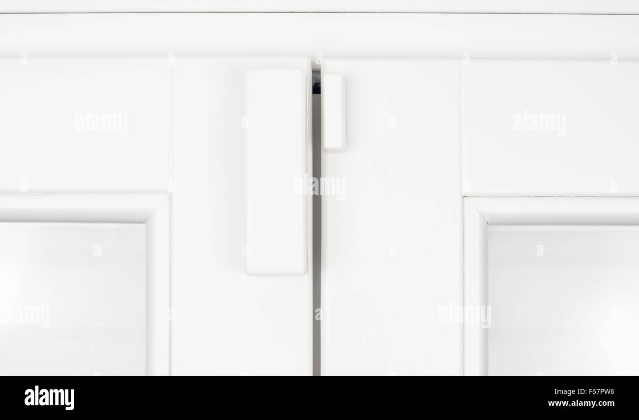 Batteria wireless magnetico del sensore di allarme per porta e finestra in legno bianco anta dettaglio Foto Stock