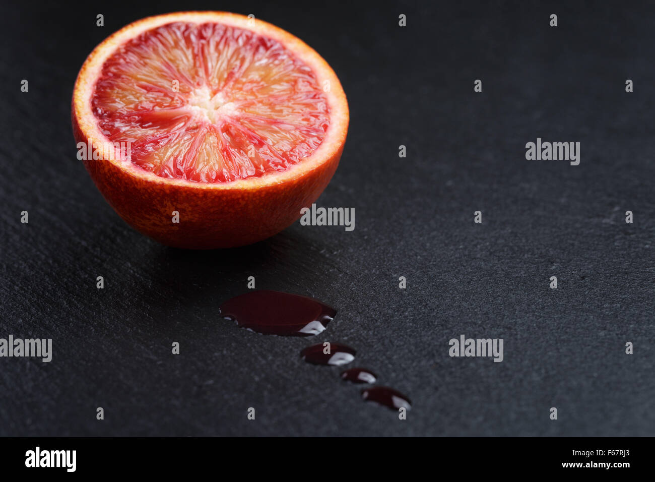 Rosso Arancio siciliano affettato sulla scheda di ardesia con gocce di succo Foto Stock