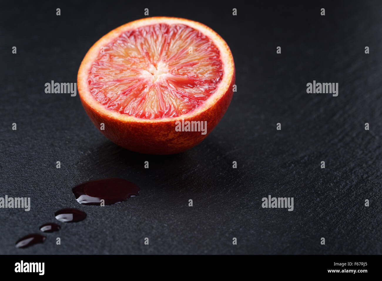 Rosso Arancio siciliano affettato sulla scheda di ardesia con gocce di succo Foto Stock