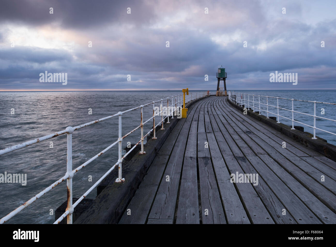 Vista lungo Whitby West Pier al crepuscolo - blu-toni di grigio delle tavole di legno, il mare e il cielo, creare una calma, atmosferici, tranquilla scena. Yorkshire, GB, UK. Foto Stock