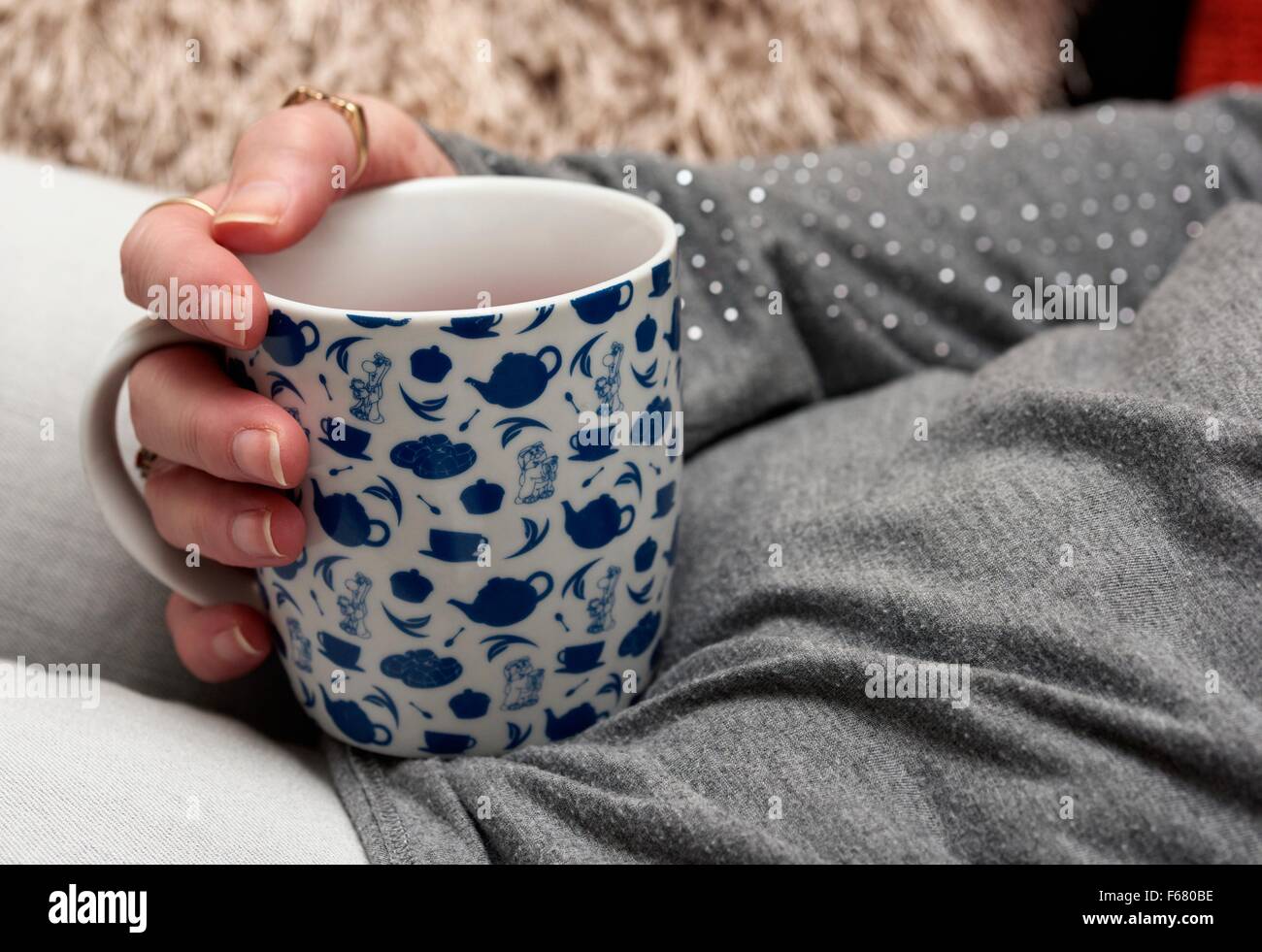 Una chiusura di una femmina di tenendo una tazza di una bevanda calda all'interno Foto Stock