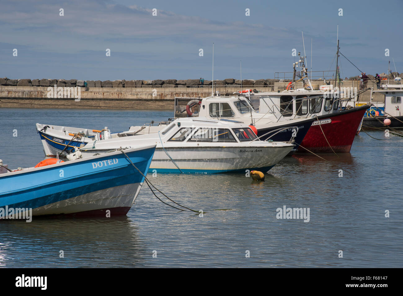 Soleggiata giornata estiva con cielo blu, piccole barche da pesca ormeggiate nel rifugio di frangiflutti e tranquilla, panoramica del porto di mare, Staithes, North Yorkshire, GB, UK. Foto Stock