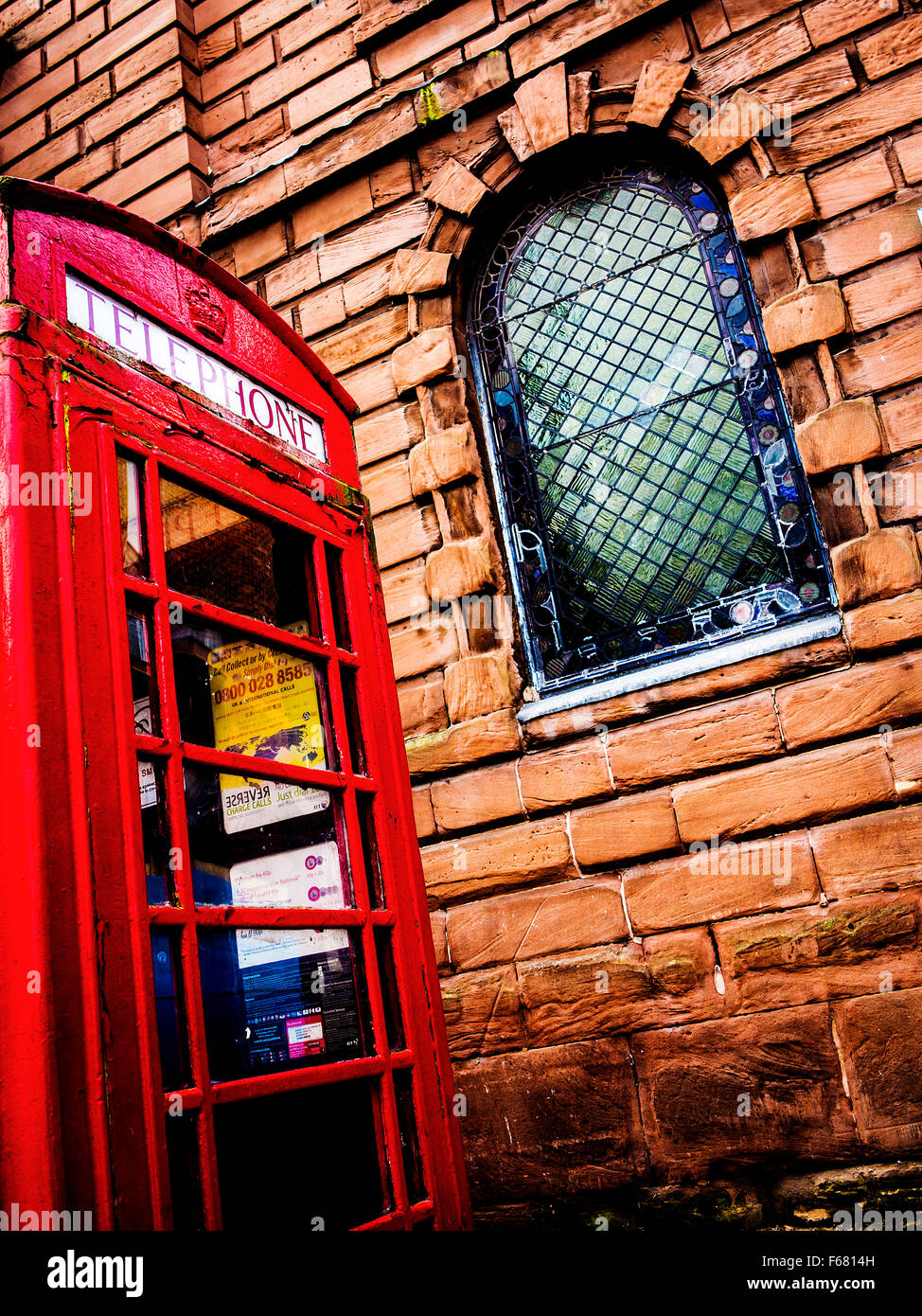 Basso angolo di visualizzazione di un vecchio telefono chiosco al di fuori della santa Chiesa della Trinità nel centro citta' di Warrington Foto Stock