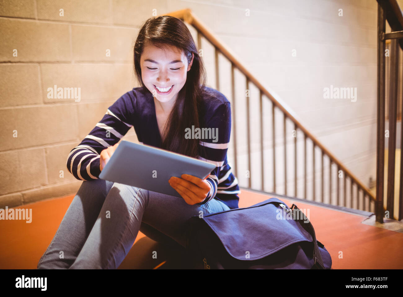 Sorridente studente seduto in corridoio con laptop Foto Stock