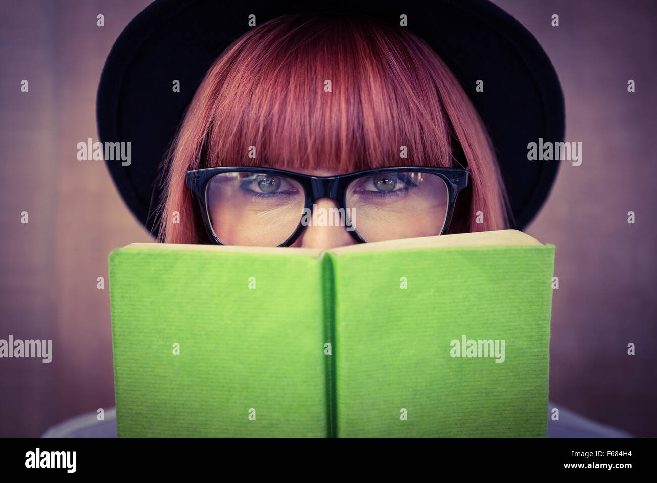 Hipster donna dietro un libro verde Foto Stock
