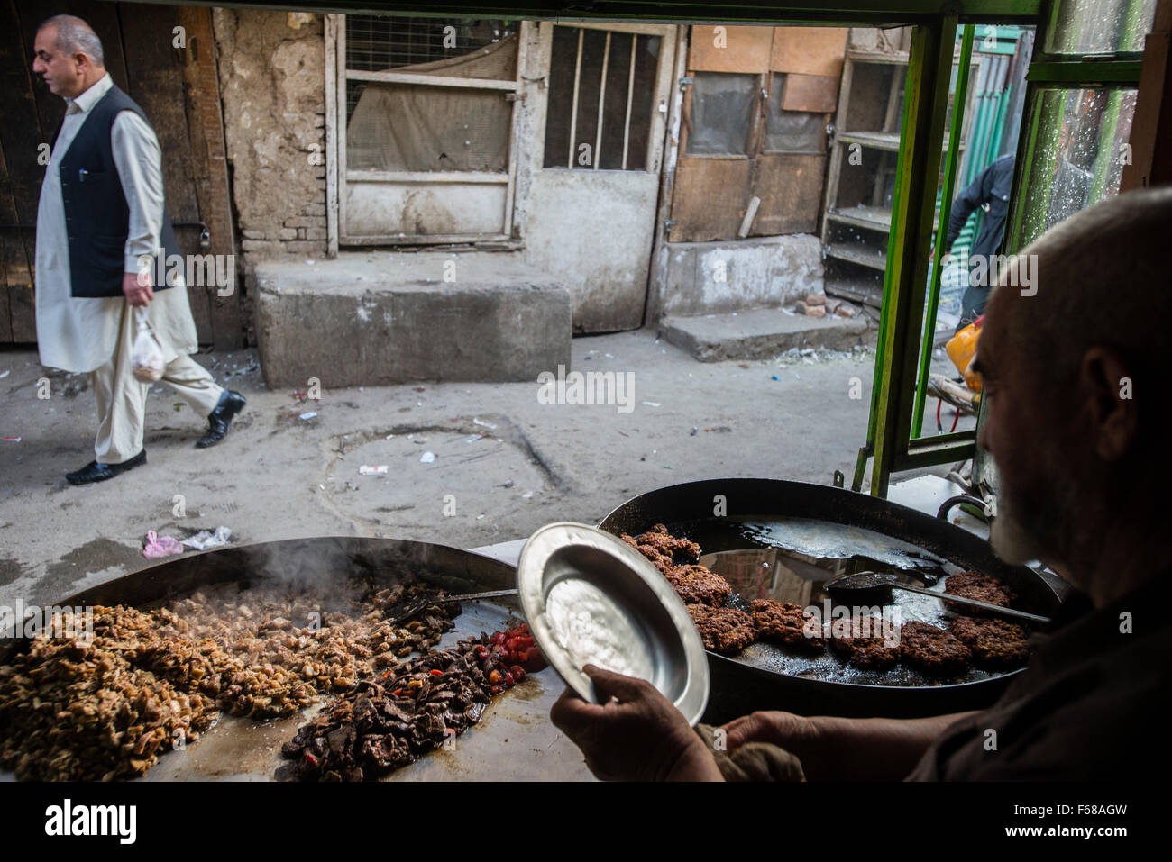 Uomo senior di preparare la carne nel ristorante tradizionale a Ka Farushi Bird's mercato, Kabul, Afghanistan Foto Stock