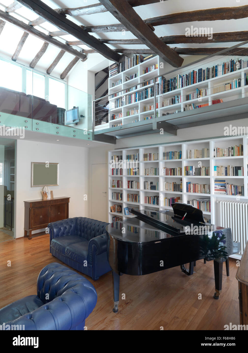 Vista interna di un classico soggiorno con un pianoforte nel centro e una biblioteca per la parete e il pavimento è in legno Foto Stock