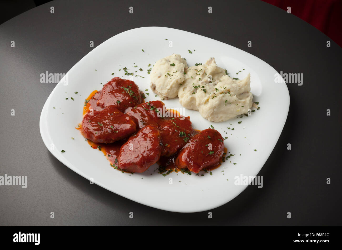 La carne di maiale in salsa rossa con purè di patate su piastra bianca Foto Stock