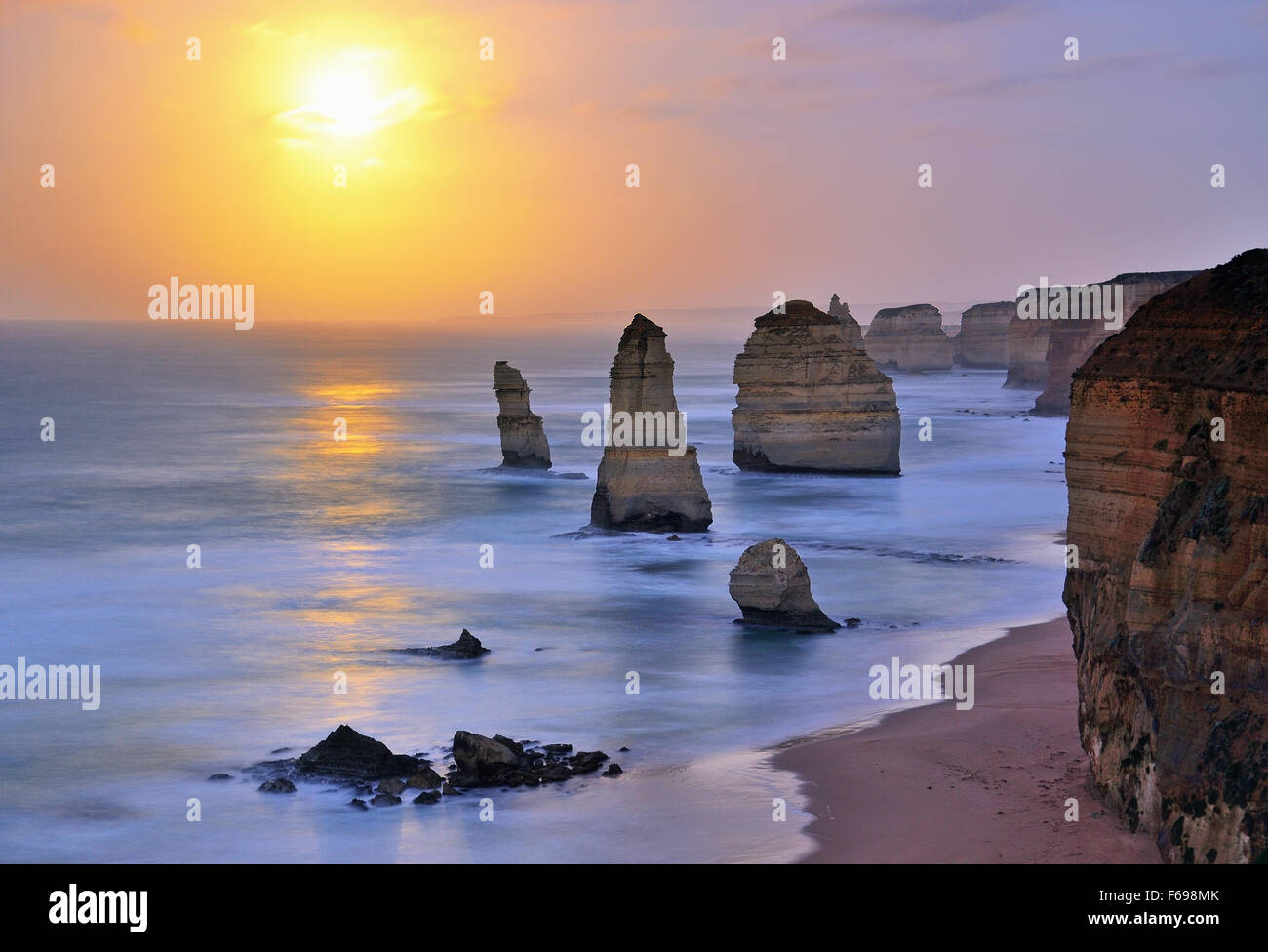 Luna tramonta oltre dodici Apostoli in Victoria, Australia. Il rumore visibile a causa di una lunga esposizione e high iso di scattare foto in condizioni di scarsa illuminazione. Foto Stock