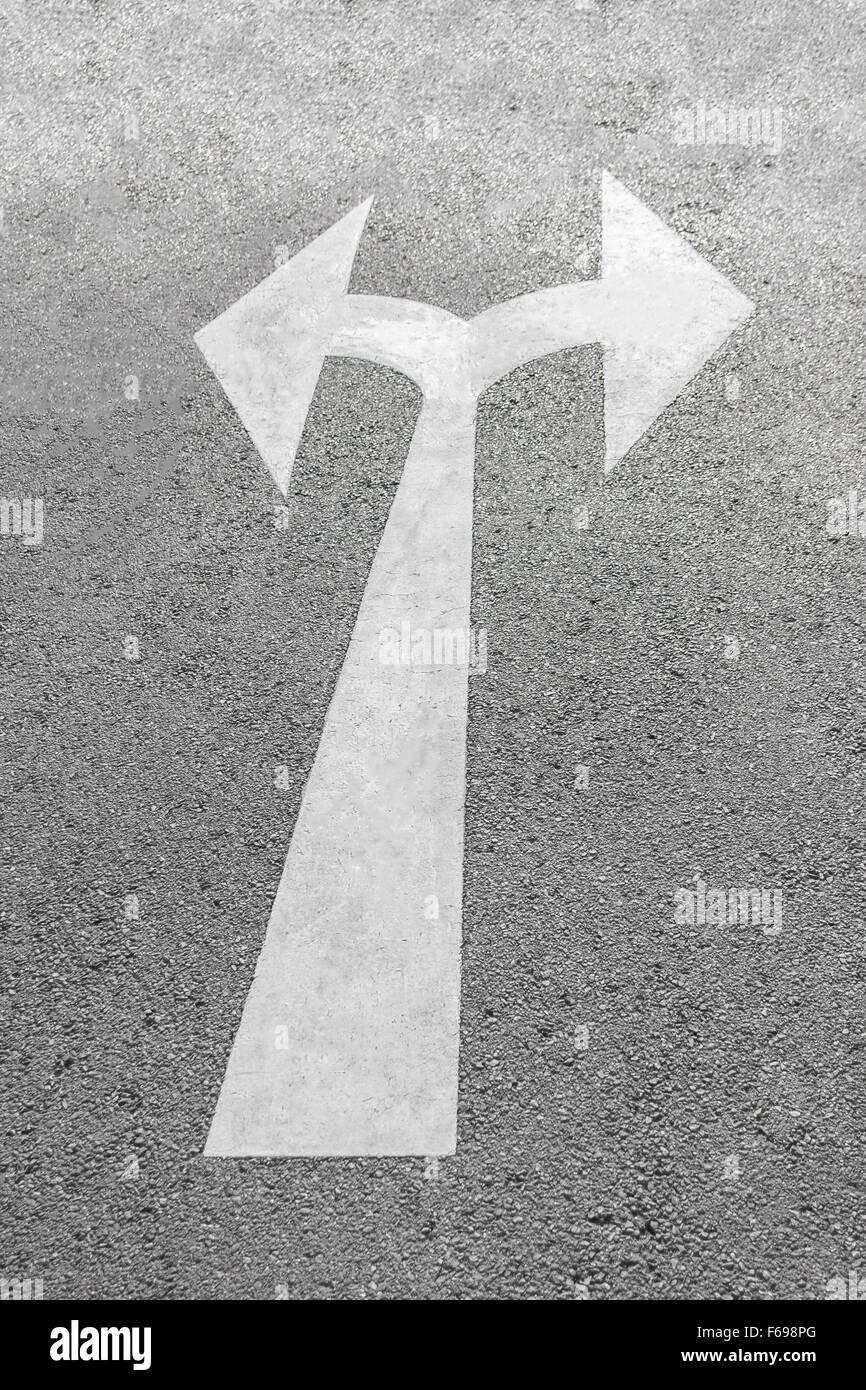 A due vie il simbolo freccia su un asfalto nero superficie stradale. Foto Stock