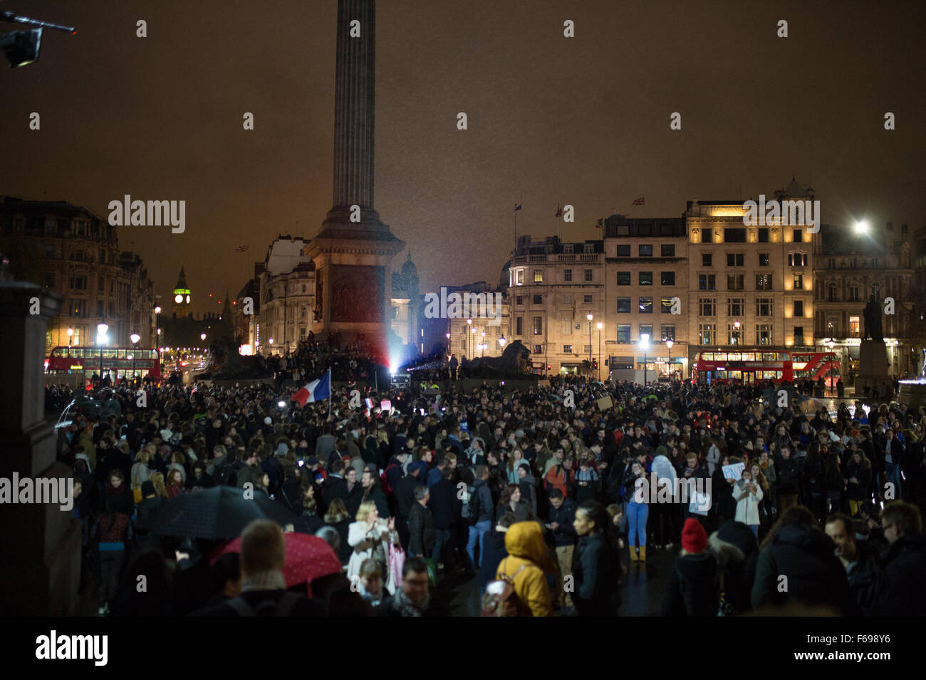 Migliaia di persone si riuniscono in Trafalgar Square, London, Regno Unito in solidarietà con il popolo francese dopo gli attentati di Parigi dove almeno 130 persone sono state uccise da una serie di attentati terroristici. Le fontane in Trafalgar Square sono accesi con il tricolore francese. La folla candele accese e ha cantato la marsigliese, l'inno nazionale francese Foto Stock
