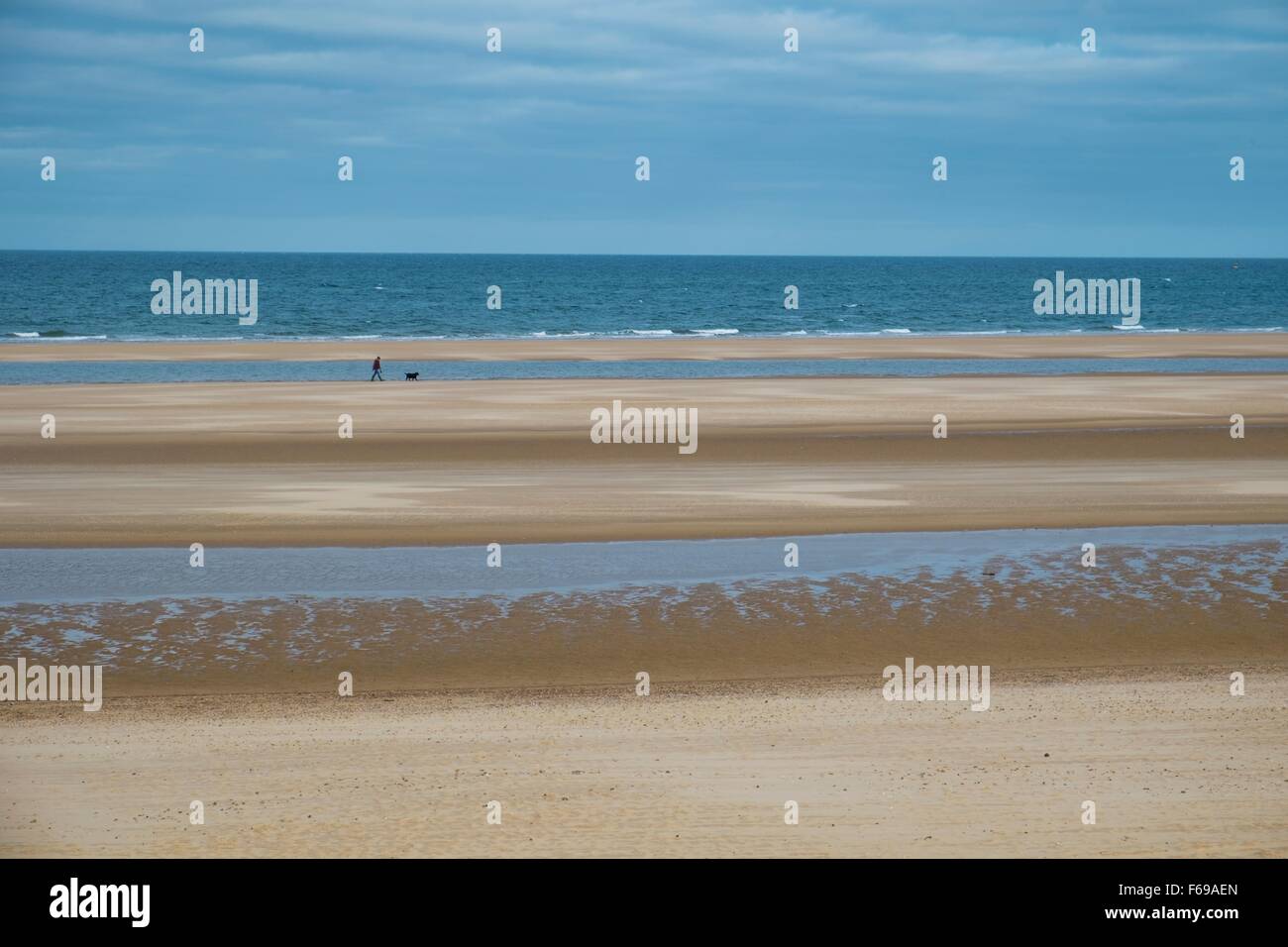 Holkham Bay, con cane walkers a distanza. Norfolk England Regno Unito Foto Stock
