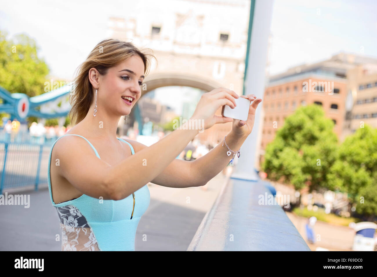 Giovane donna di scattare una foto da Tower Bridge con il suo telefono Foto Stock