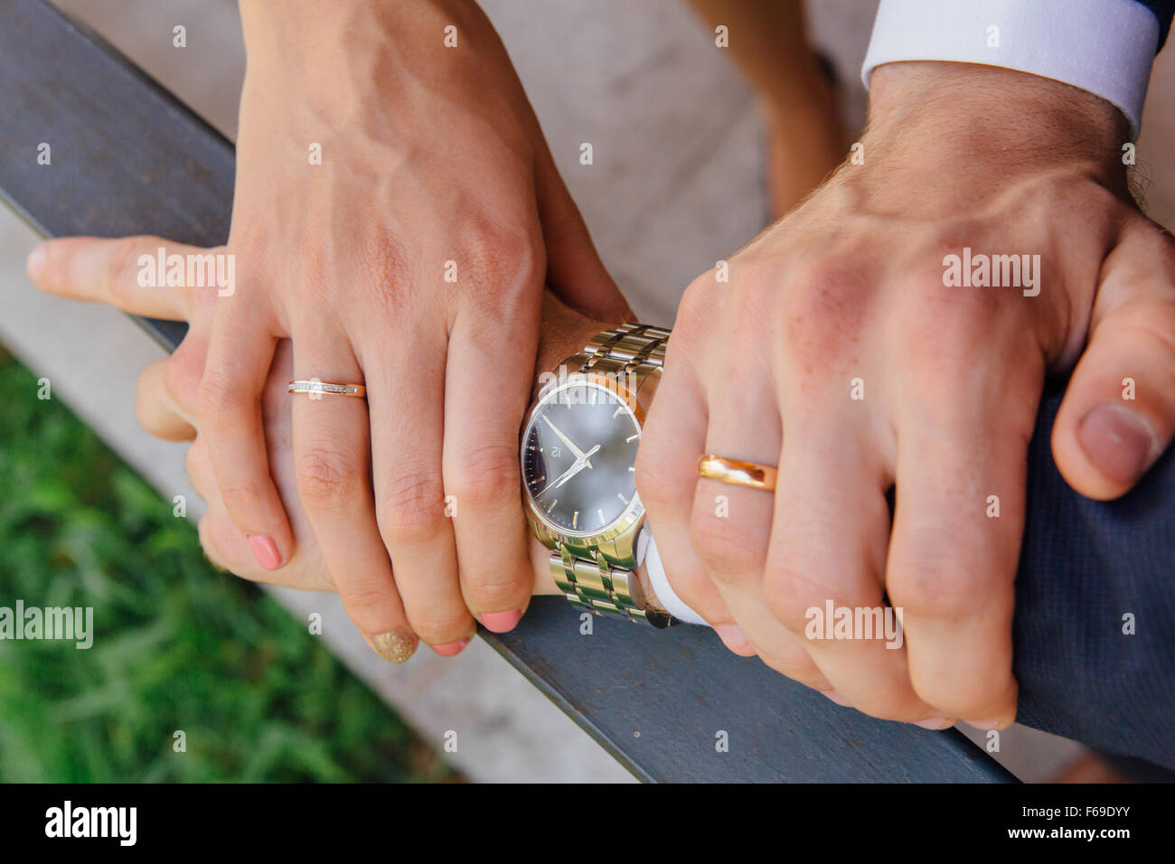 Le mani di un uomo e di una donna con gli anelli di nozze sulla Le Mans il  polso con orologio Foto stock - Alamy