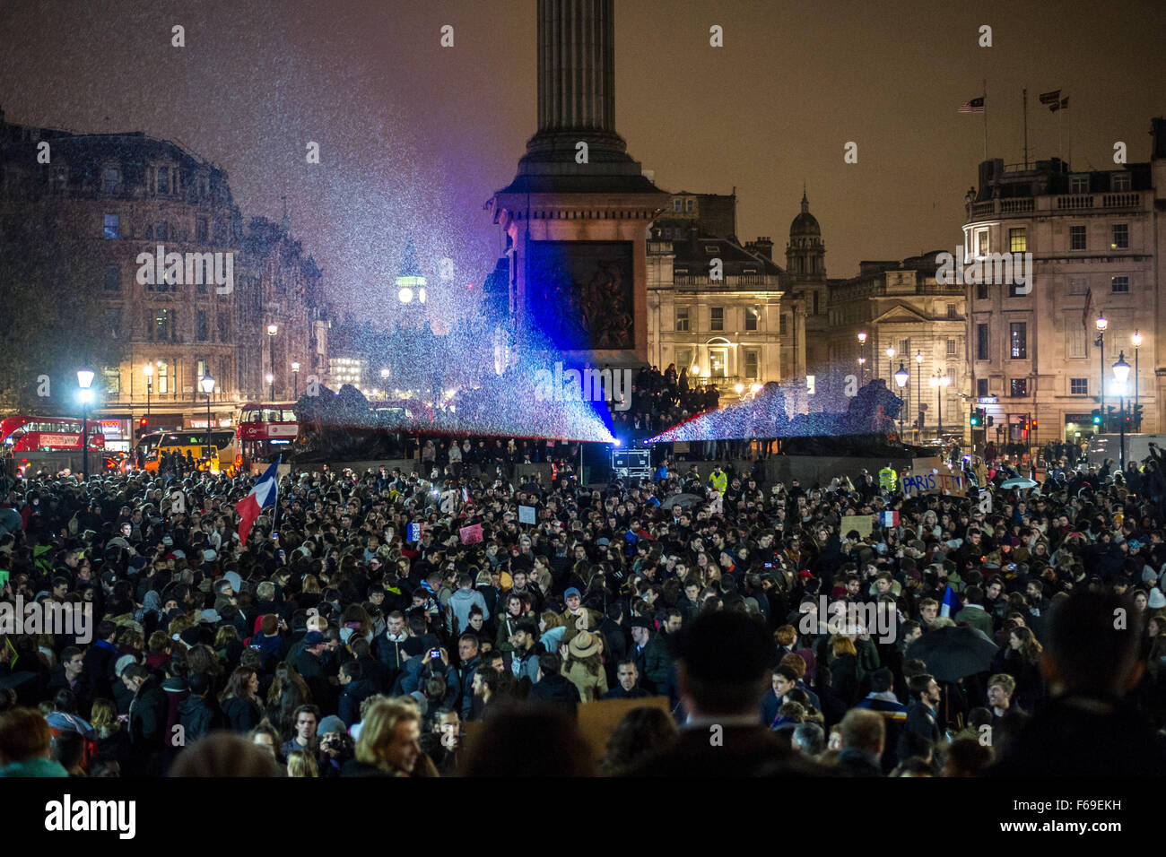 Londra, Regno Unito. 14 Novembre, 2015. Migliaia di fedeli in Trafalgar Square per una veglia a lume di candela in solidarietà con le vittime della scorsa notte di attacchi terroristi a Parigi. La National Portrait Gallery è illuminata con i colori del tricolore francese bandiera. Foto Stock