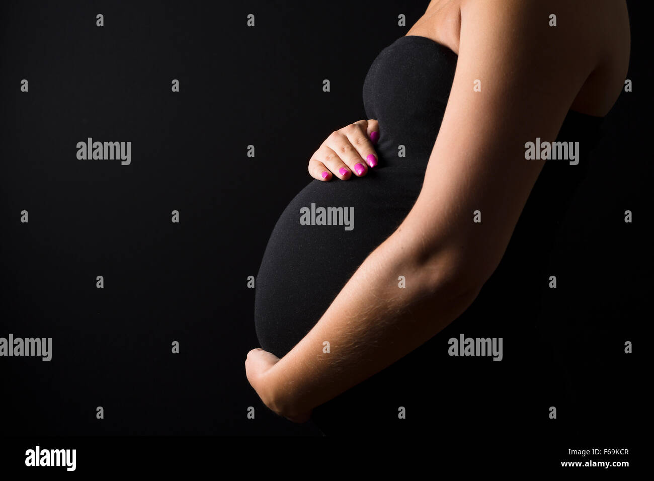Giovane donna in stato di gravidanza sta con le mani in corrispondenza del ventre Foto Stock