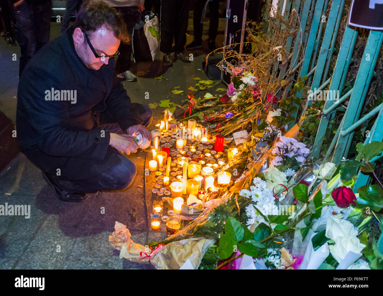 Parigi, Francia, attacchi terroristici di Bataclan, fiori del lutto pubblico all'aperto, candele Man Lighting vicino a Street Foto Stock