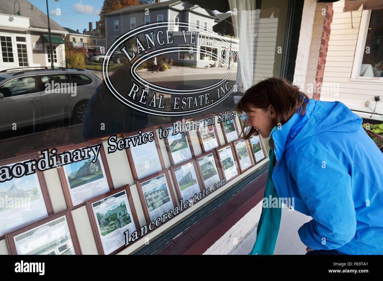 Una donna che guarda in un agenti immobiliari finestra, Lenox, Massachusetts MA USA Foto Stock
