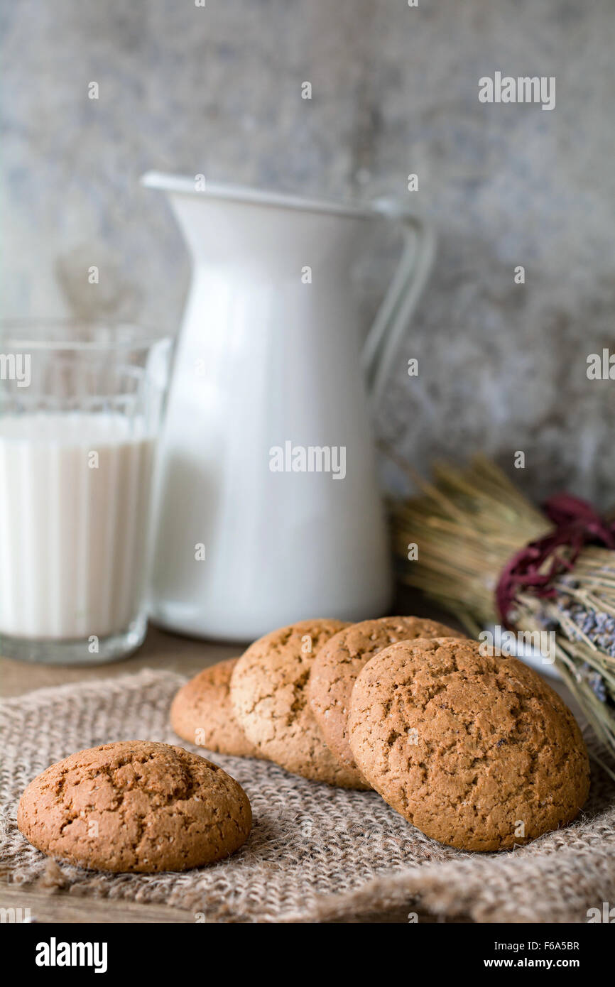 Chocolate Chip Cookie di fiocchi d'avena, lavanda essiccata e latte sul panno di lino. Campagna ancora vita Foto Stock