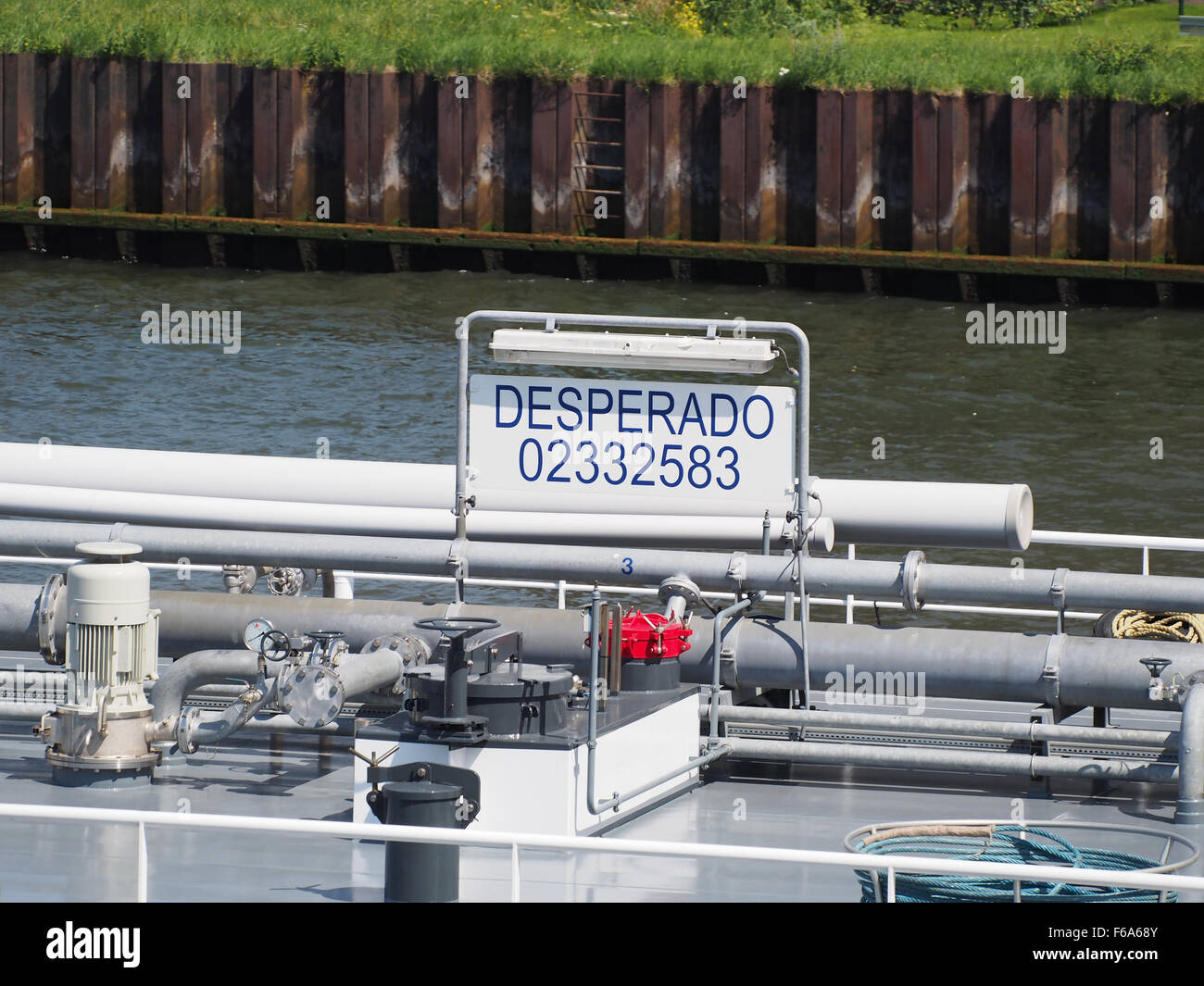La nave portacontainer "Desperado" (ENI 02332583) è mostrata navigando nella Amsterdam-Rijnkanaal, caricata con una varietà di merci tra cui contenitori, petrolio, carbone e cereali. Le operazioni della nave sono sostenute da gru portuali, che sottolineano la logistica del trasporto di beni generici e forniture di energia. Foto Stock