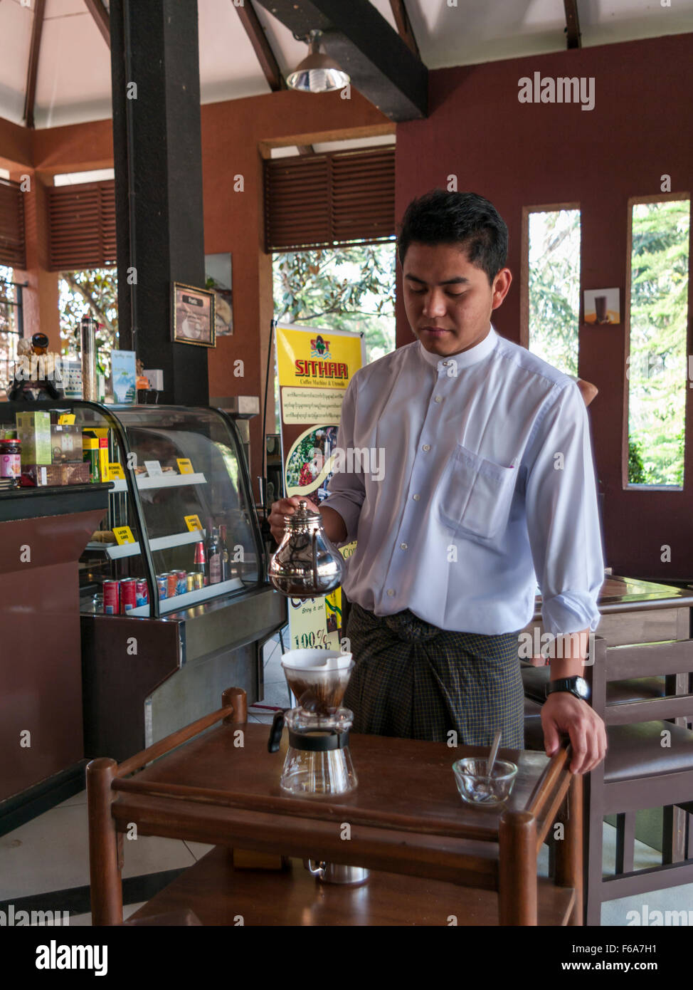 Cameriere in un caffè di Pyin Oo Lwin (Maymyo) in Myanmar la preparazione del caffè fresco, versando acqua calda oltre il caffè macinato. Foto Stock