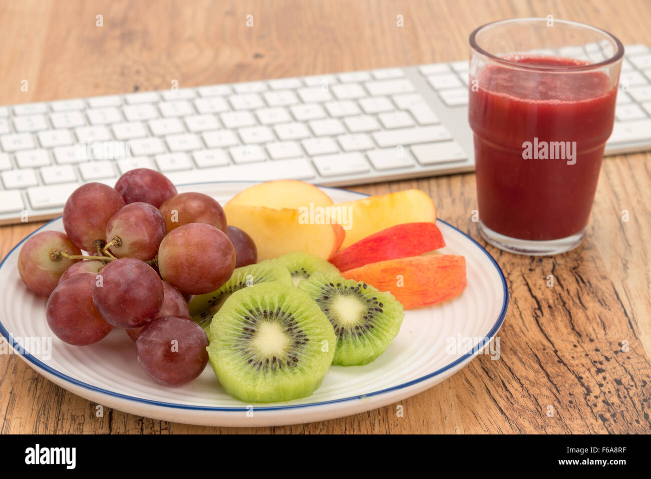 Un sano piatto di frutta e un frullato di lamponi pranzo presso la scrivania in ufficio - close-up Foto Stock