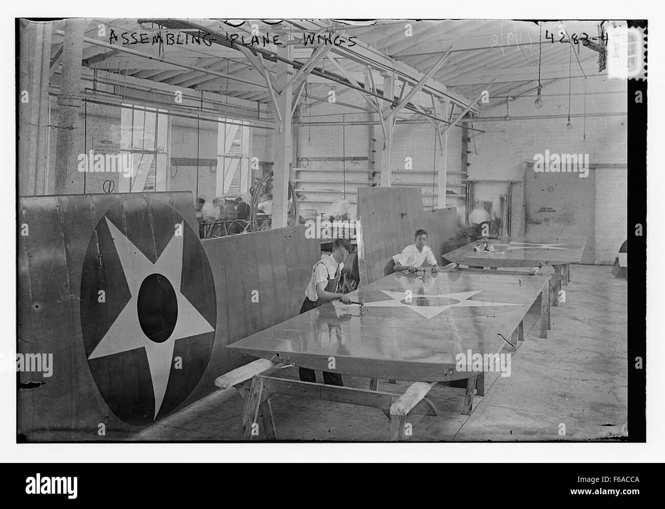 Un'immagine di lavoratori che assemblano le ali di un aereo in fabbrica. Questa fotografia raffigura probabilmente il processo di produzione di aeromobili, mostrando i lavoratori coinvolti nella costruzione di componenti vitali per l'aviazione. Foto Stock