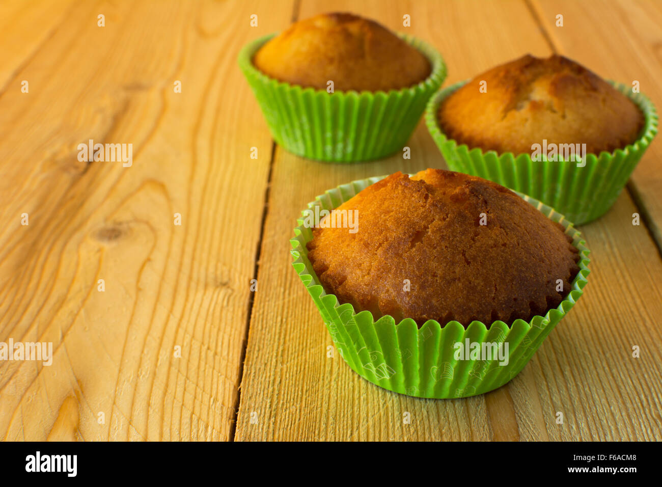 Muffin nel libro verde cupcake titolare su un sfondo di legno orizzontale, il fuoco selettivo Foto Stock