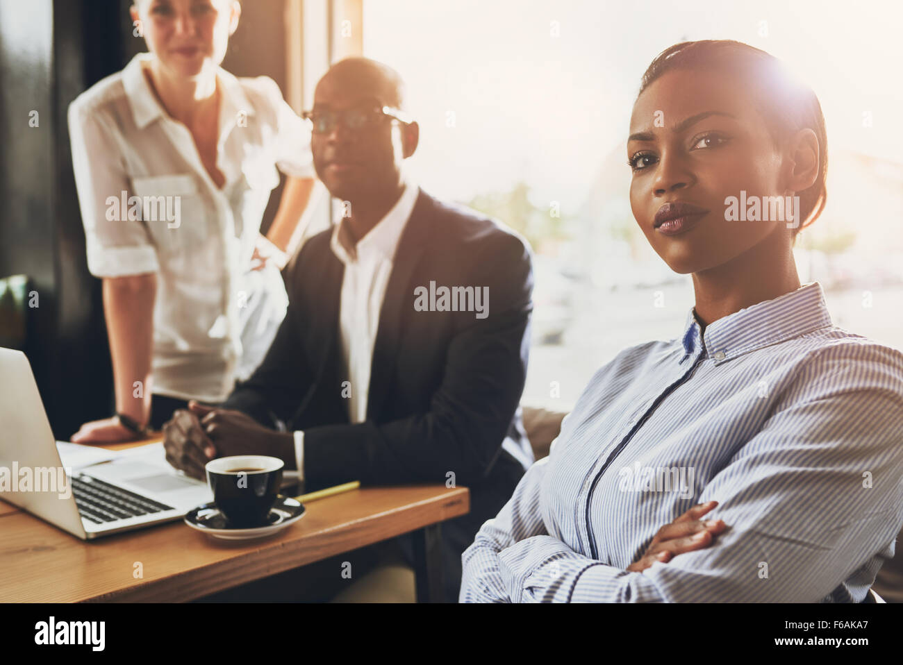 Fiducioso giovane nero business donna seduta davanti ad altre persone di affari Foto Stock