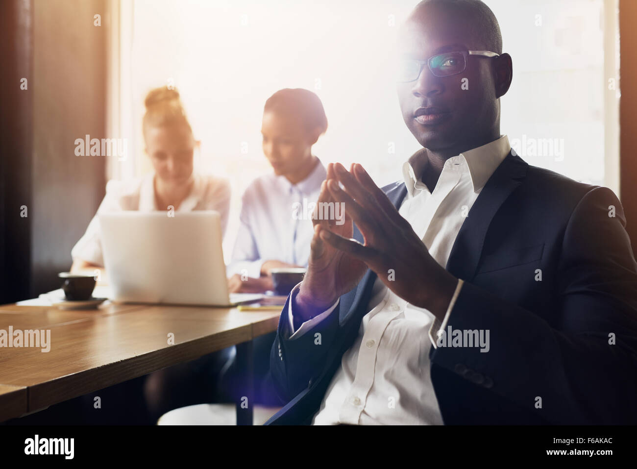 Grave business nero uomo seduto di fronte ai suoi dipendenti in ufficio Foto Stock