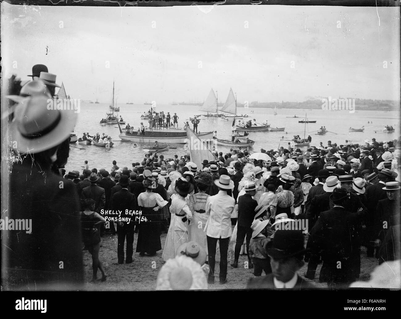 Questa fotografia cattura l'atmosfera di Capodanno a Shelly Beach ad Auckland, mostrando l'atmosfera rilassata e festosa degli amanti della spiaggia che si godono le vacanze estive. L'immagine riflette la bellezza costiera e il popolare luogo di svago in nuova Zelanda. Foto Stock