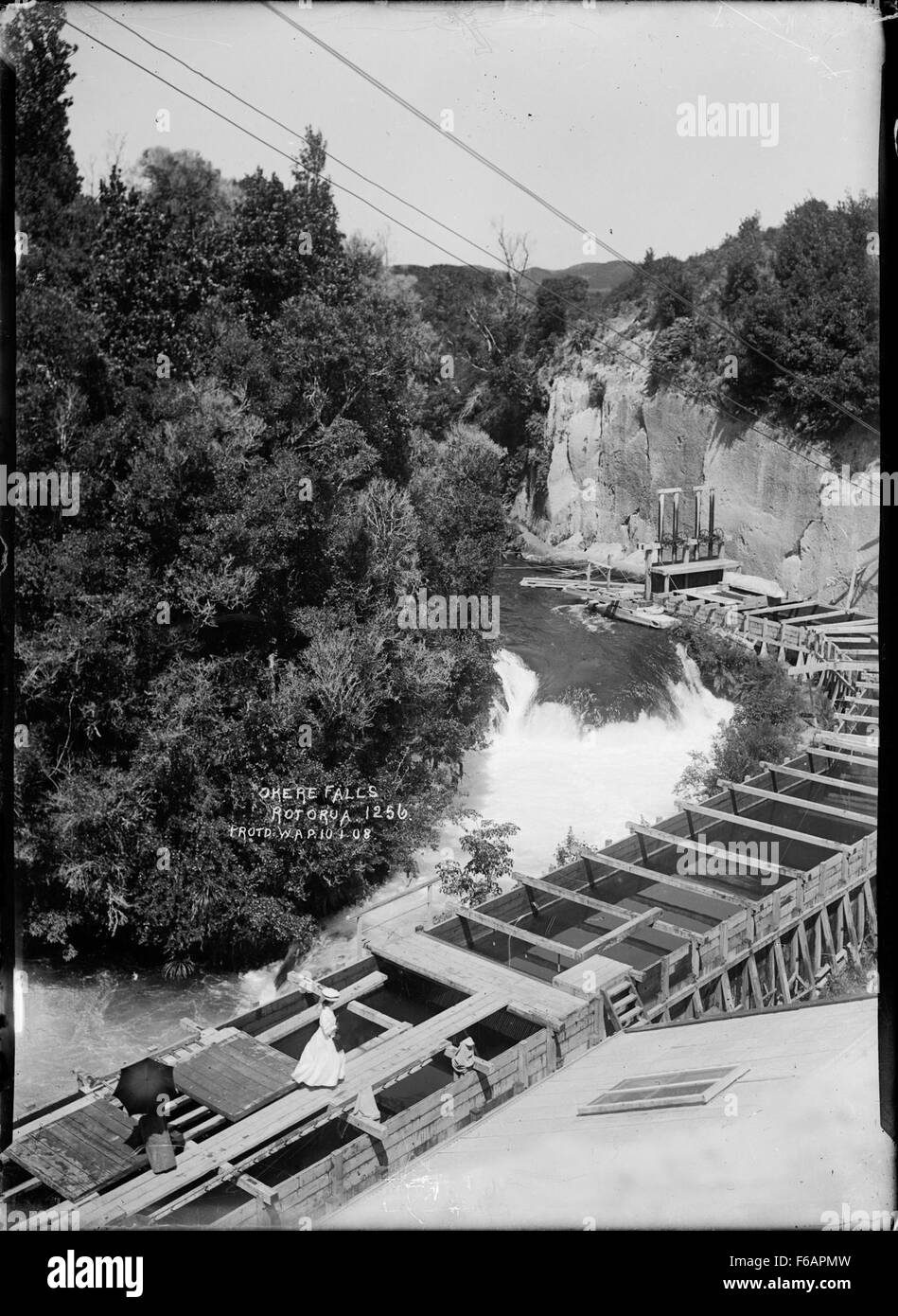 Questa immagine raffigura la centrale elettrica di Okere Falls nel distretto di Rotorua, nuova Zelanda. La fotografia evidenzia l'architettura industriale della centrale elettrica e la sua integrazione con l'ambiente naturale circostante. Foto Stock