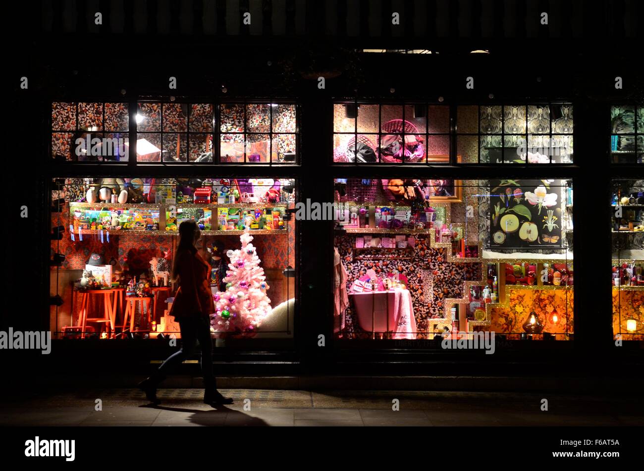 Una signora passando il Natale 2015 finestra al negozio di Liberty in serata, Great Marlborough Street, London, England, Regno Unito Foto Stock