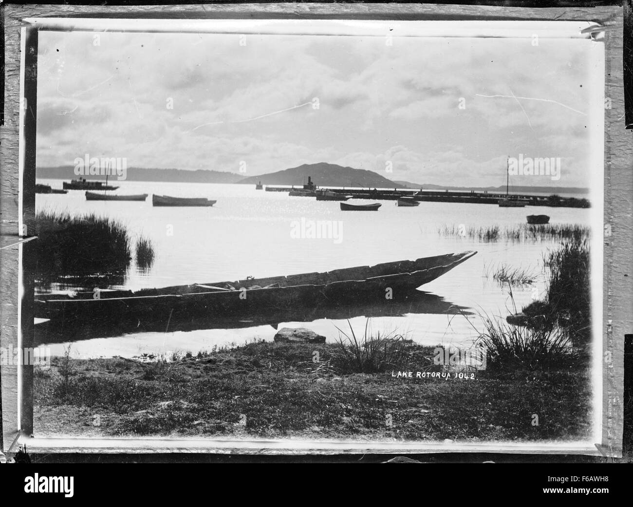Questa opera d'arte ritrae le barche vicino al litorale del lago Rotorua, catturando la bellezza serena del lago e del suo paesaggio circostante. La scena mostra l'interazione tra acqua e terra in un ambiente tranquillo. Foto Stock