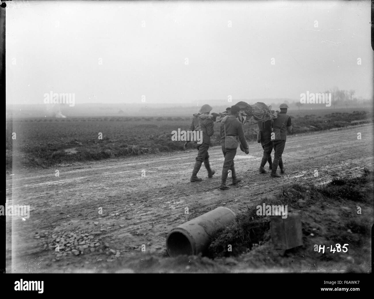 Questa immagine cattura una scena straziante della prima guerra mondiale, mostrando i soldati che portano i compagni feriti mentre sono sotto fuoco. L'immagine riflette i pericoli della guerra e la resilienza dei soldati in tali condizioni. Foto Stock