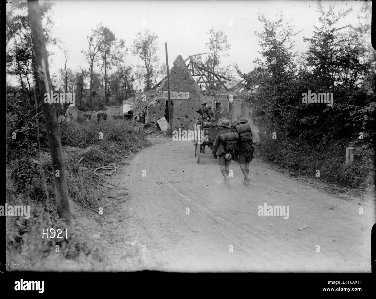 Una fotografia storica che raffigura una batteria di artiglieria neozelandese che avanza in un villaggio catturato durante le operazioni militari. L'immagine riflette il movimento tattico e la strategia militare del tempo. Foto Stock