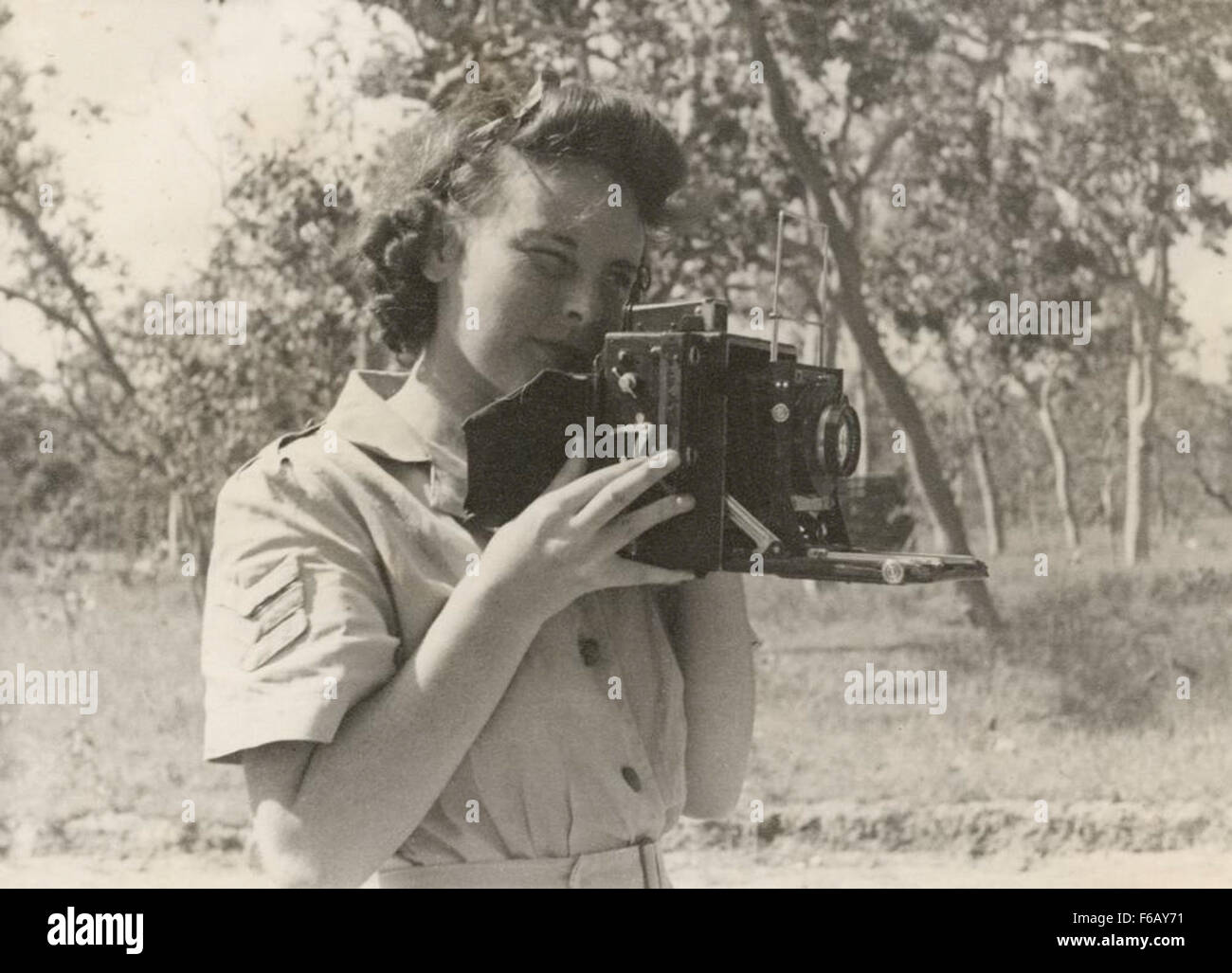 Questa immagine storica mostra il sergente Olive Lucas che utilizza una fotocamera Speed Graphic 4x5 nel Queensland. È stata riqualificata come fotografa dopo l'esposizione al gas di senape, catturando momenti di guerra come parte della Australian Chemical Warfare Research and Experimental Section. Foto Stock