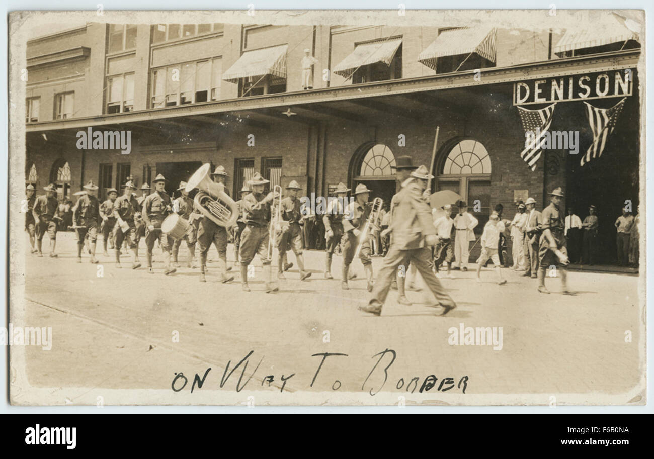 Questa vera cartolina fotografica (RPPC) cattura una cerimonia militare o una sfilata, con bande e truppe sulla strada per un confine. Mostra la precisione e la disciplina del personale dell'esercito degli Stati Uniti coinvolto nell'evento. Foto Stock