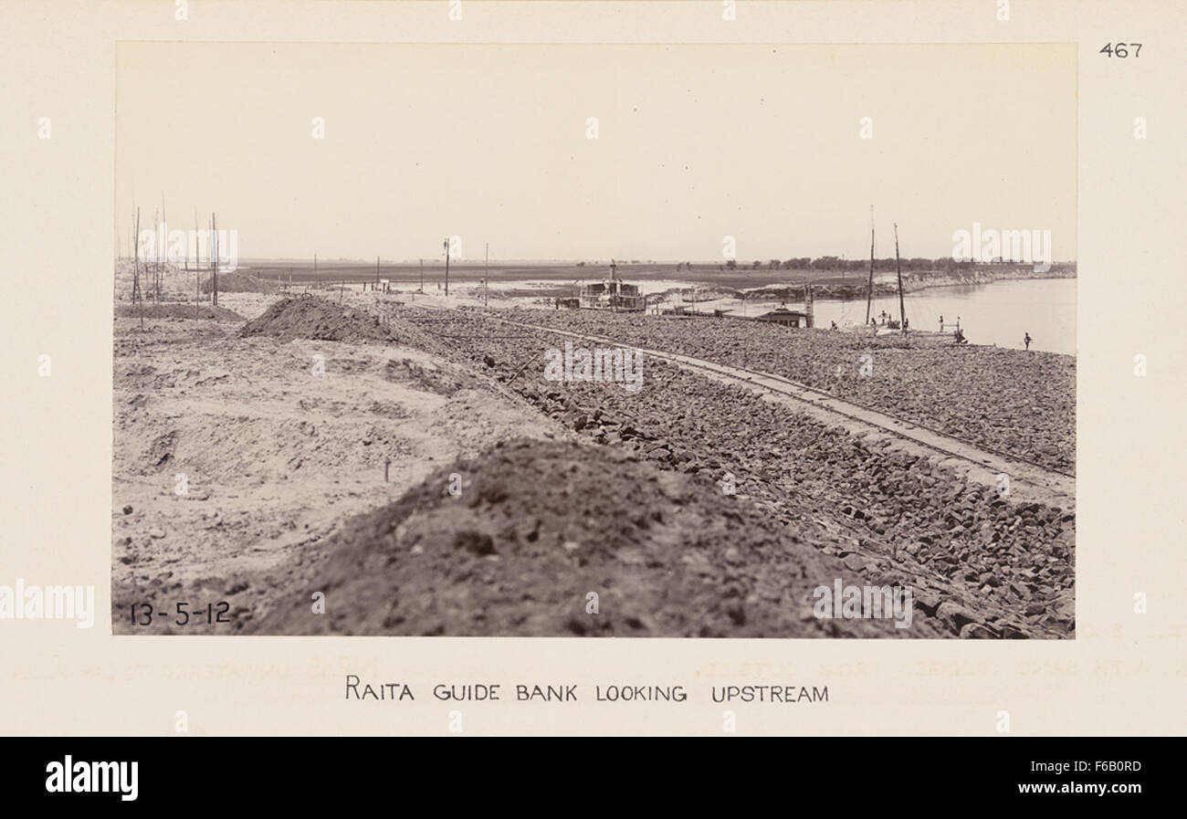 Una fotografia che mostra una vista di una sponda del fiume con la Raita Guide Bank in primo piano, insieme alla costruzione di ponti per una ferrovia. L'immagine cattura il continuo sviluppo delle infrastrutture ferroviarie. Foto Stock