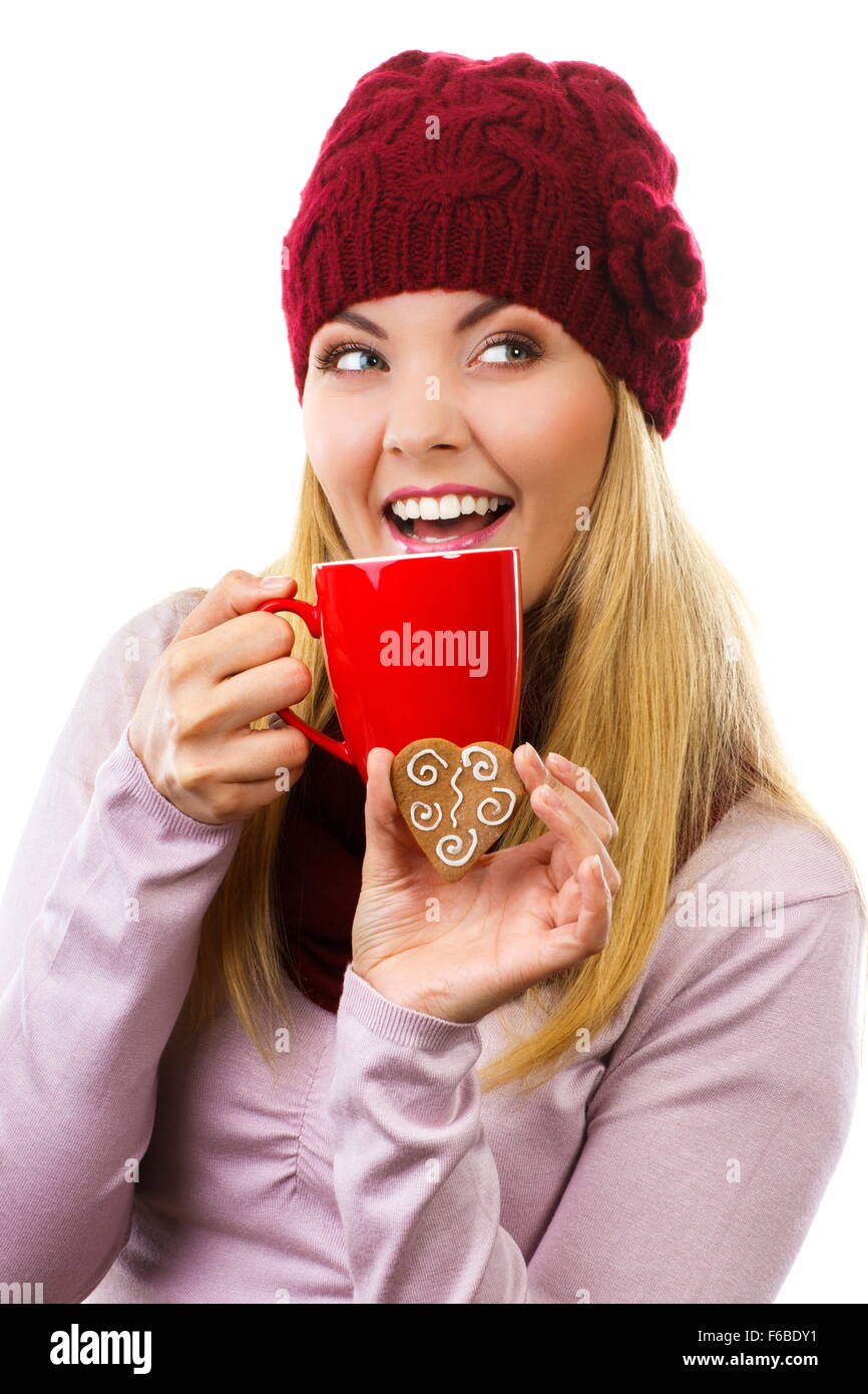 Donna sorridente indossando cappello di lana e scialle holding decorate gingerbread o biscotti di Natale e rosso tazza di tè o caffè caldo, Foto Stock