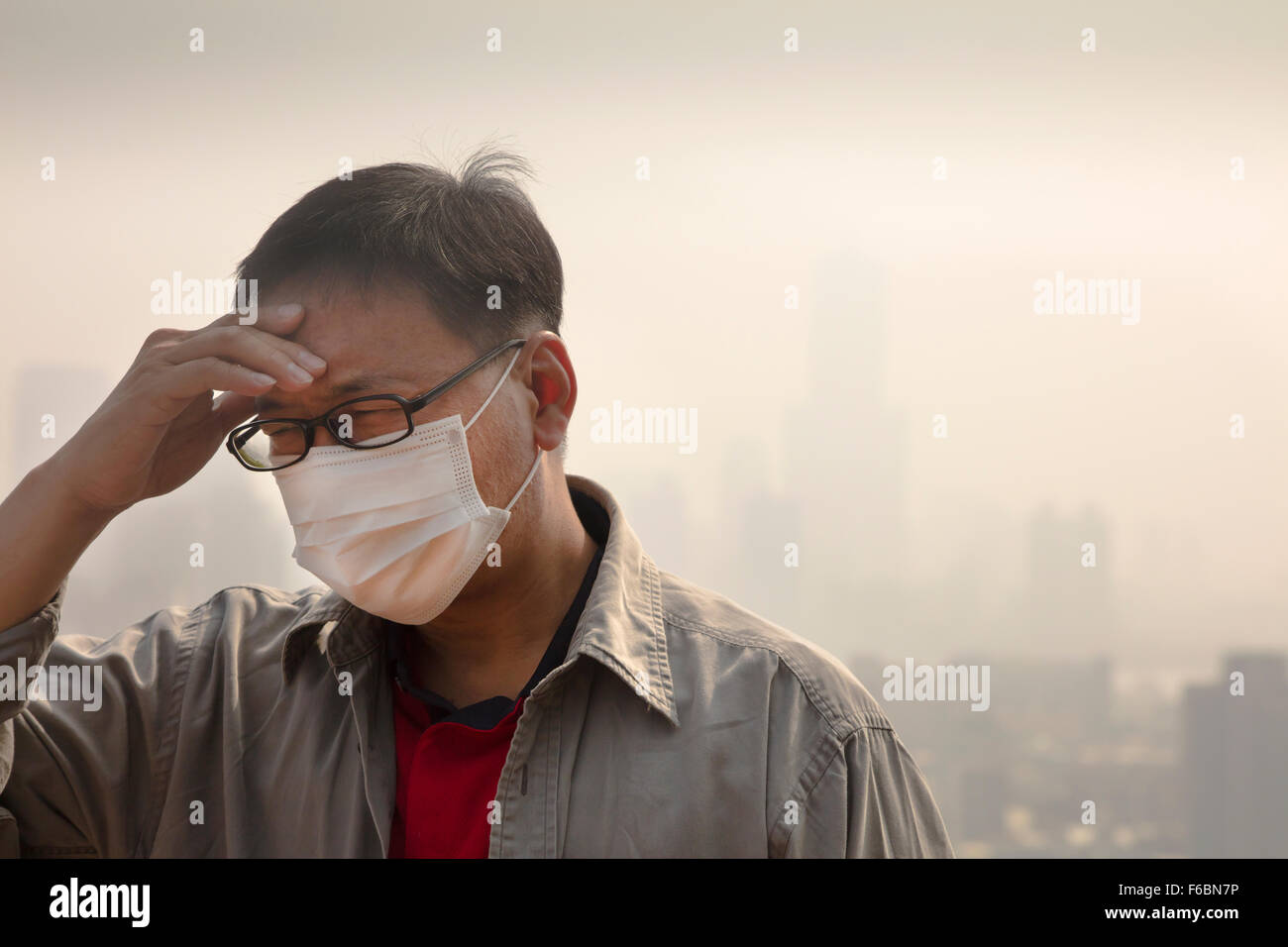 Uomo asiatico che indossa la maschera di bocca contro l'inquinamento atmosferico Foto Stock