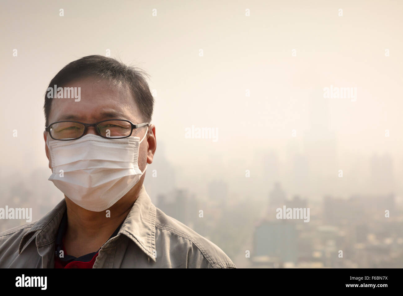 Uomo asiatico che indossa la maschera di bocca contro l'inquinamento atmosferico Foto Stock