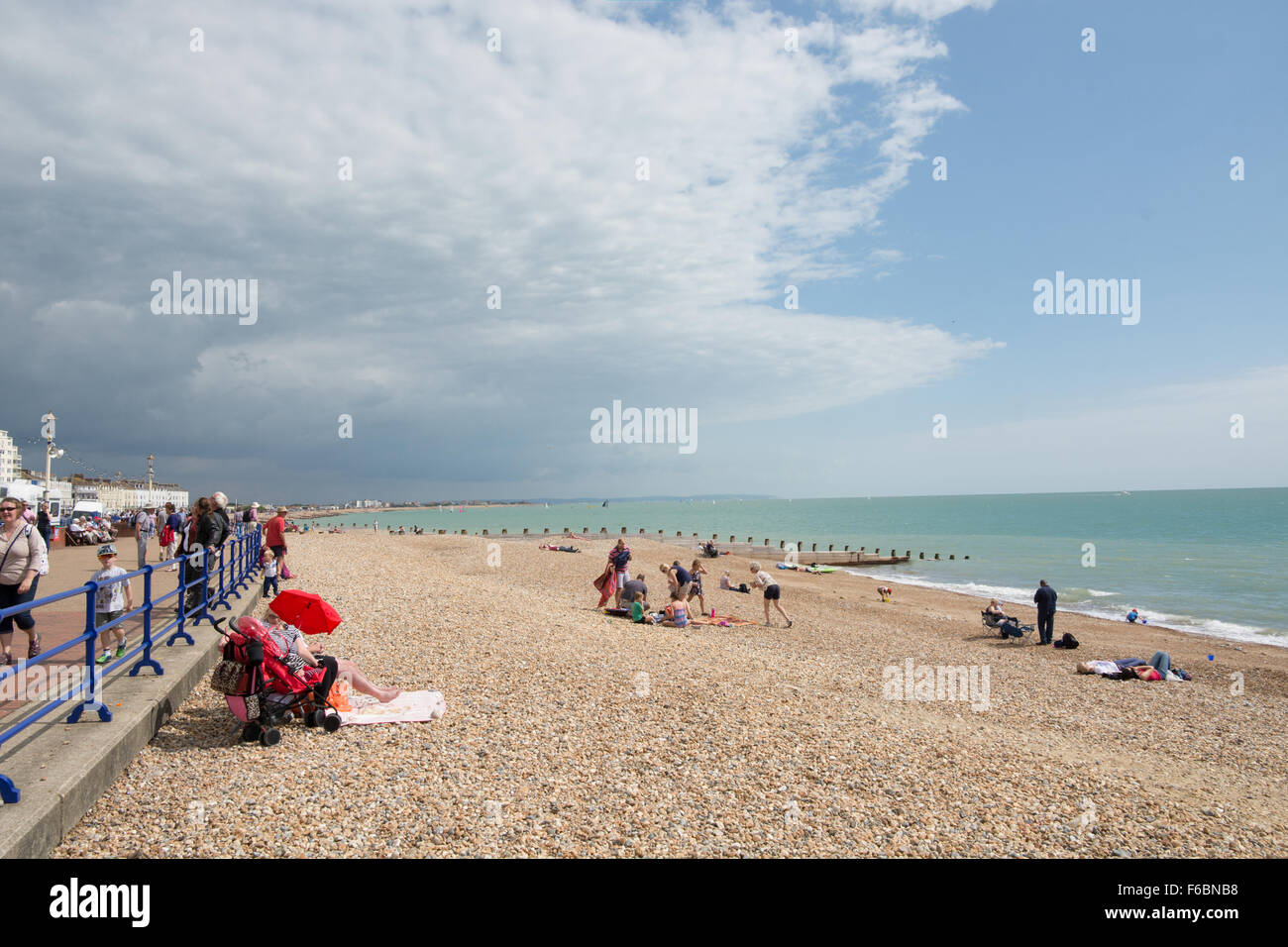 Le famiglie potranno usufruire di una pausa sul stoney spiaggia a Easbourne. Il cloud che si profila all'orizzonte bottino vi giorno? Foto Stock