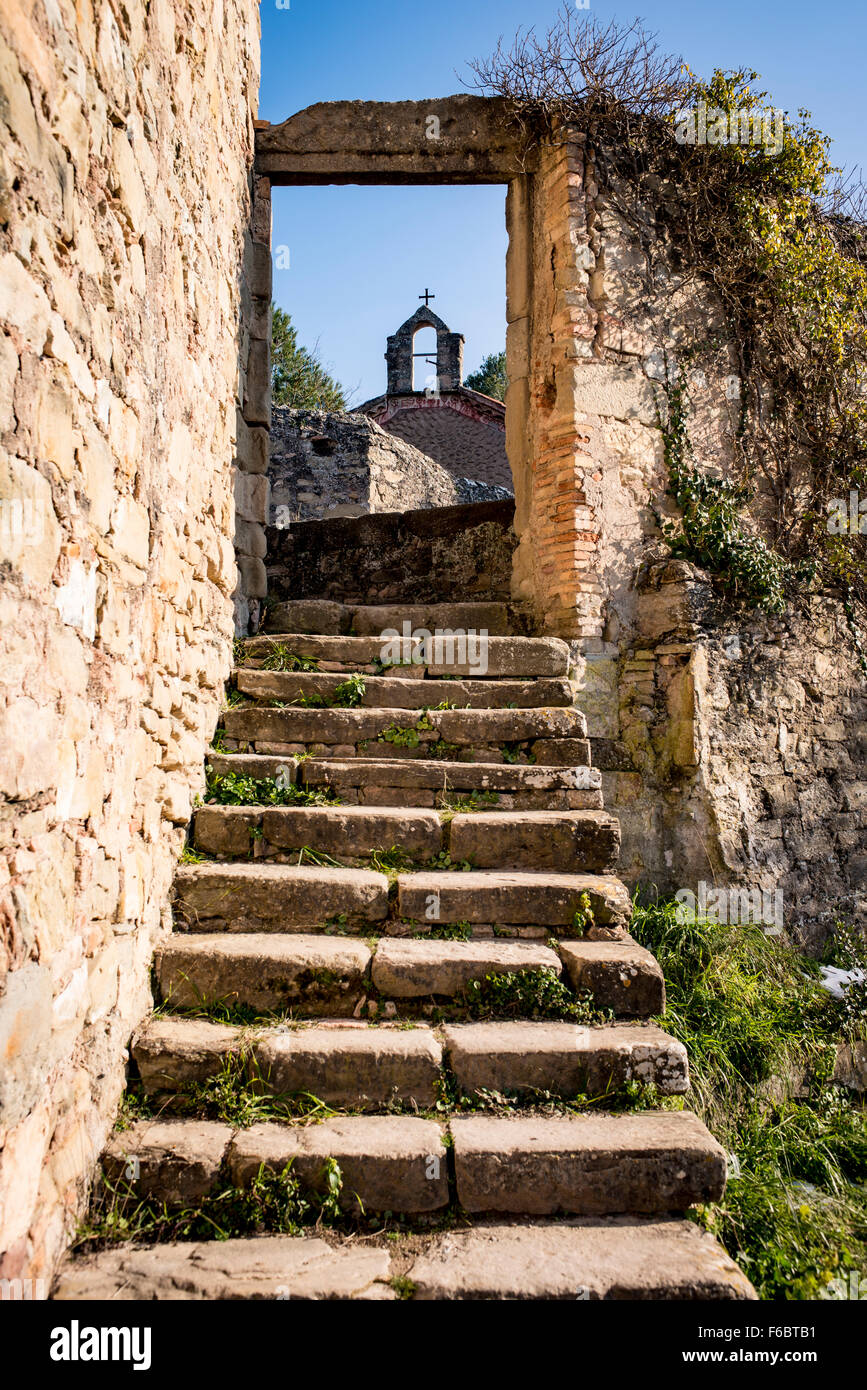 I resti di una vecchia fabbrica abbandonata con una chiesa in background. Foto Stock