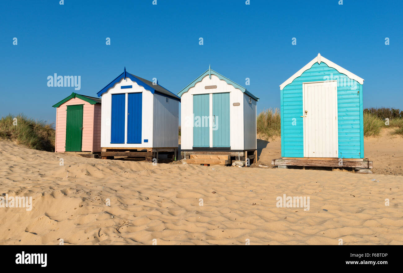 Una fila di capanne clouful su di una spiaggia di sabbia sostenuta da dune a Southwold sulla costa di Suffolk Foto Stock