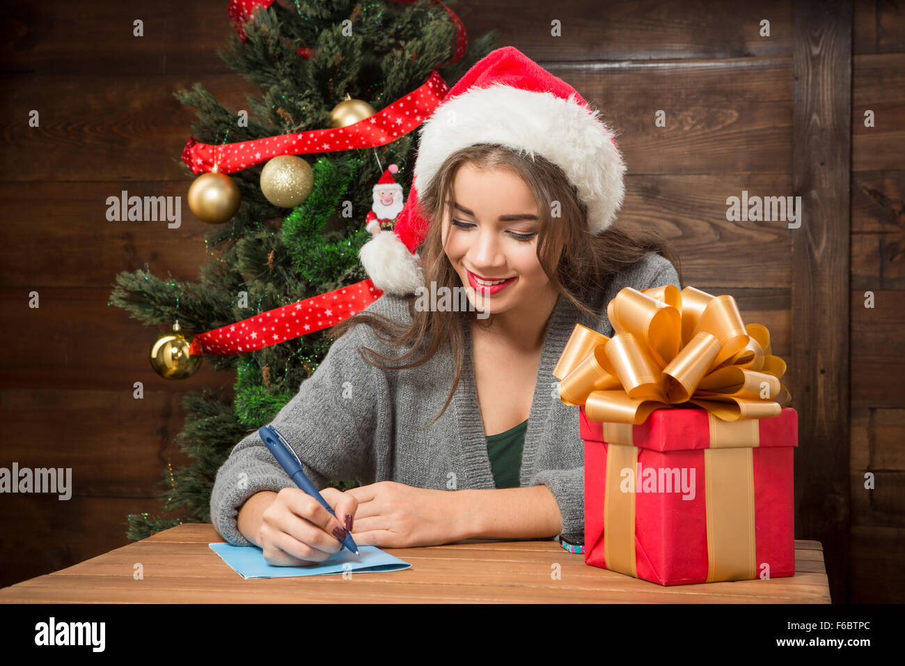 Bella ragazza scrivere un Nuovo Anno e saluti di Natale Foto Stock