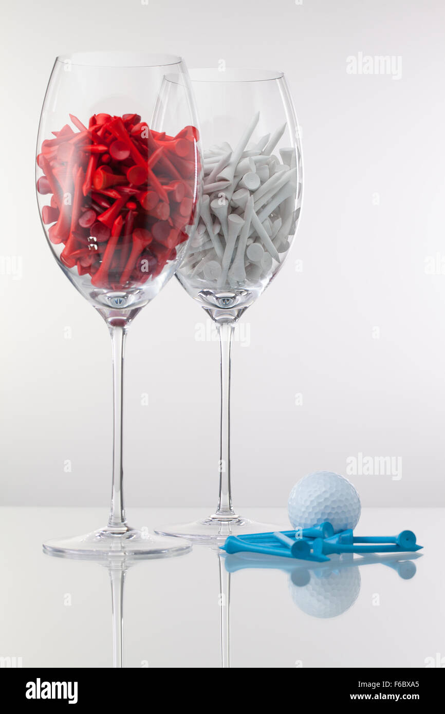 Due bicchieri di vino e attrezzature da golf su sfondo bianco Foto Stock