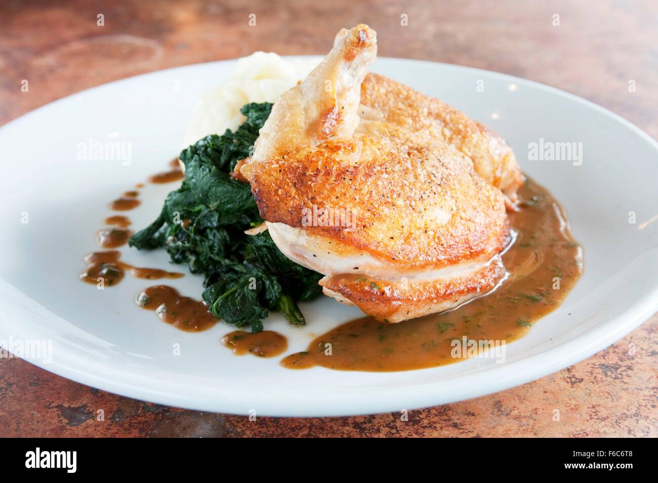 Pollo arrosto con spinaci appassito e sugo di carne Foto Stock