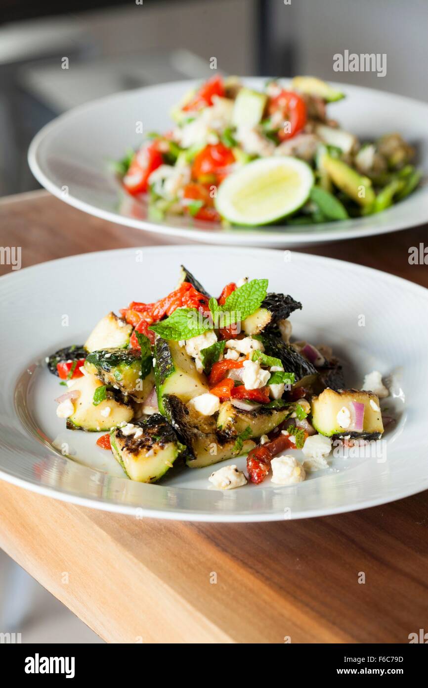 Mediterraneo Insalata di zucchine con peperoni rossi, cipolla rossa e formaggio feta; insalata di granchio in background Foto Stock